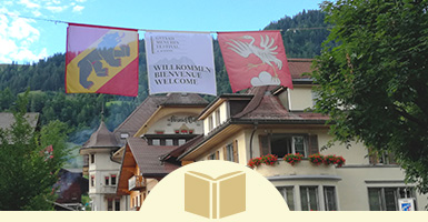 スイスベルン州の旗とザーネン市の旗及びその街の建物と山の風景